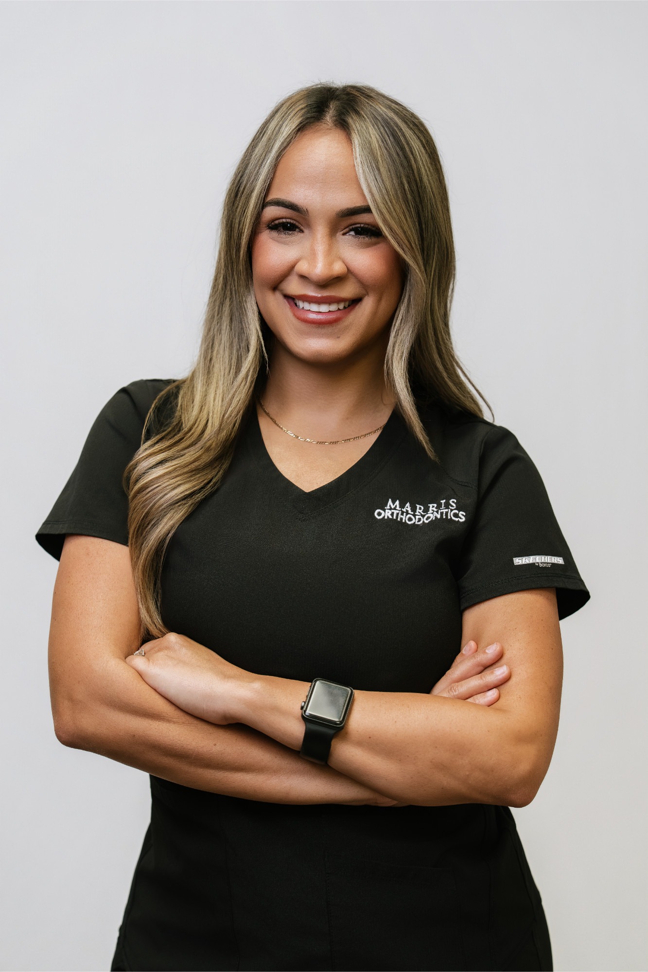 Smiling female staff member in black scrubs with "Marris Orthodontics" logo, showcasing expertise in orthodontics and patient care, representing the best orthodontist in Orlando.