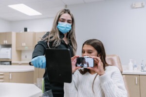 Dental professional assisting patient with smartphone in orthodontic office, showcasing innovative Dental Monitoring technology at Marris Orthodontics, Orlando.