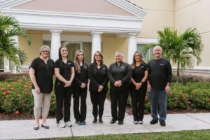 Marris Orthodontics team members standing outside their Orlando practice, showcasing friendly staff in black attire, emphasizing orthodontic services like braces and Invisalign in Orlando.